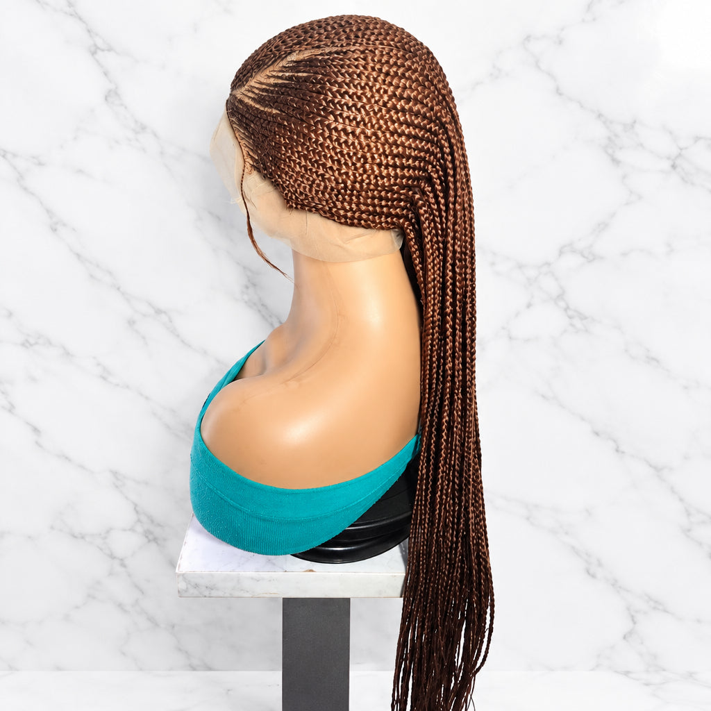 The wig features a dark brown base with warm golden-brown highlights throughout the braids.