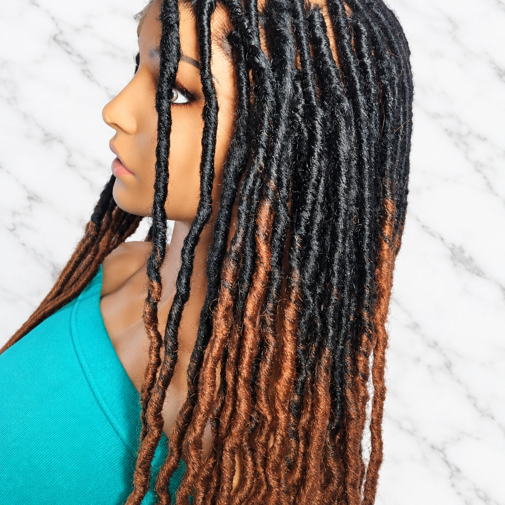 A close-up side profile of long dreadlock braided wig with a dark brown to black root transitioning into warm coppery brown lengths